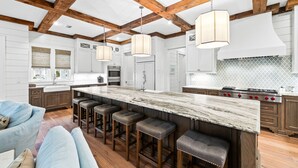 Una cocina moderna con una isla grande, vigas de madera y taburetes de bar.