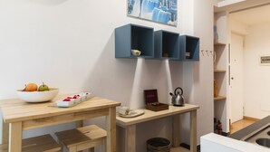 A modern kitchen with a wooden table, a bowl of fruit, and a painting of a waterfall. - notaMi - Dimora Certosa (Milan)