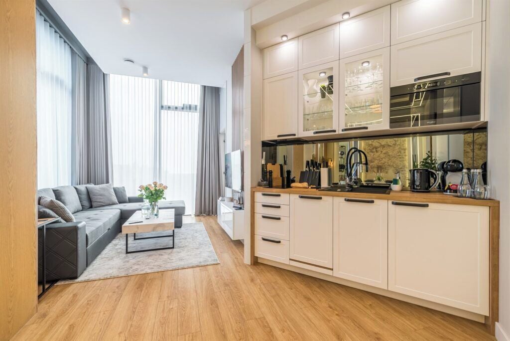 Una sala de estar moderna con un sofá, una mesa de centro y una cocina con armarios y electrodomésticos.