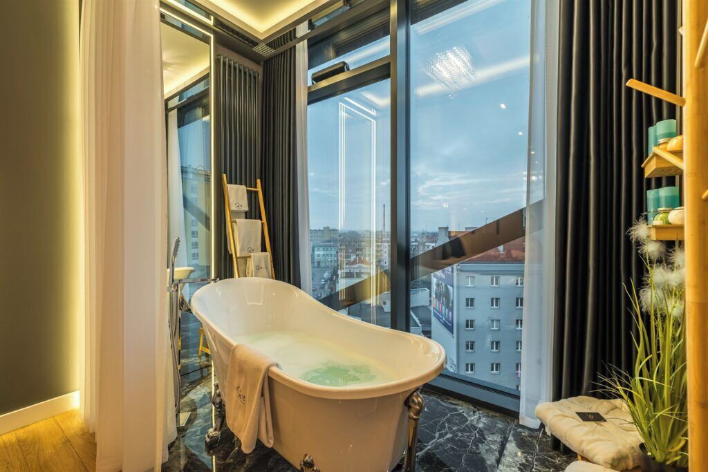 Une salle de bain moderne avec une baignoire sur pieds, de grandes fenêtres et une vue sur la ville.