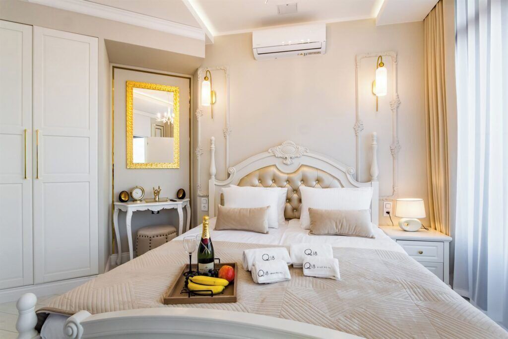 A hotel room with a large bed, a bedside table with a lamp, a mirror, and a wardrobe.