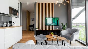 A modern living room with a grey sofa, a coffee table, and a TV mounted on a wall with vertical wooden slats.