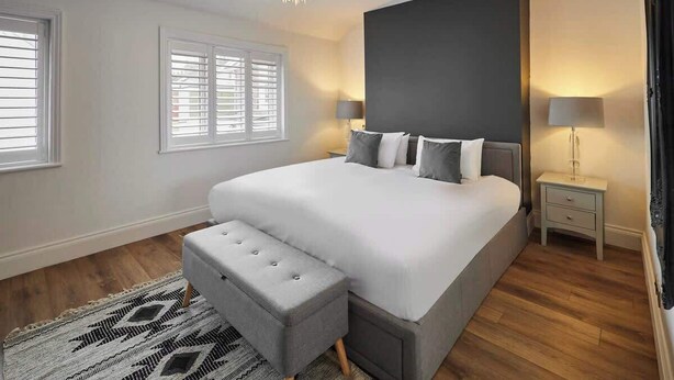 Una camera da letto con un letto grande, un tavolino, una panca e un lampadario.