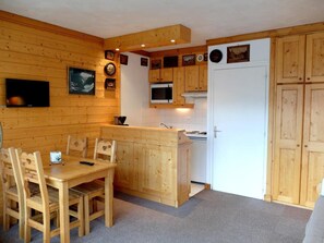 A compact kitchen with wooden cabinetry, a microwave, and a small dining area with chairs. - 100m from resort center, 4th floor, balcony, tv, ski locker, 28m², Tignes (Tignes)