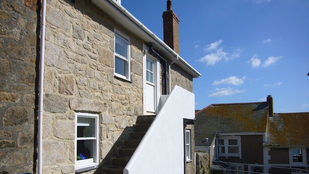 A stone building with a white staircase leading to a door.