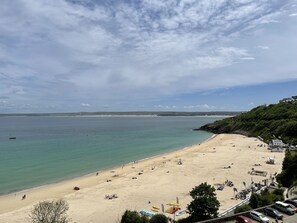 A beach with a clear view of the sea, sandy shore, and a few people.