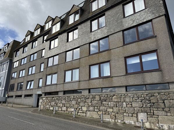 A multi-story building with a stone facade, multiple windows, and a visible entrance.