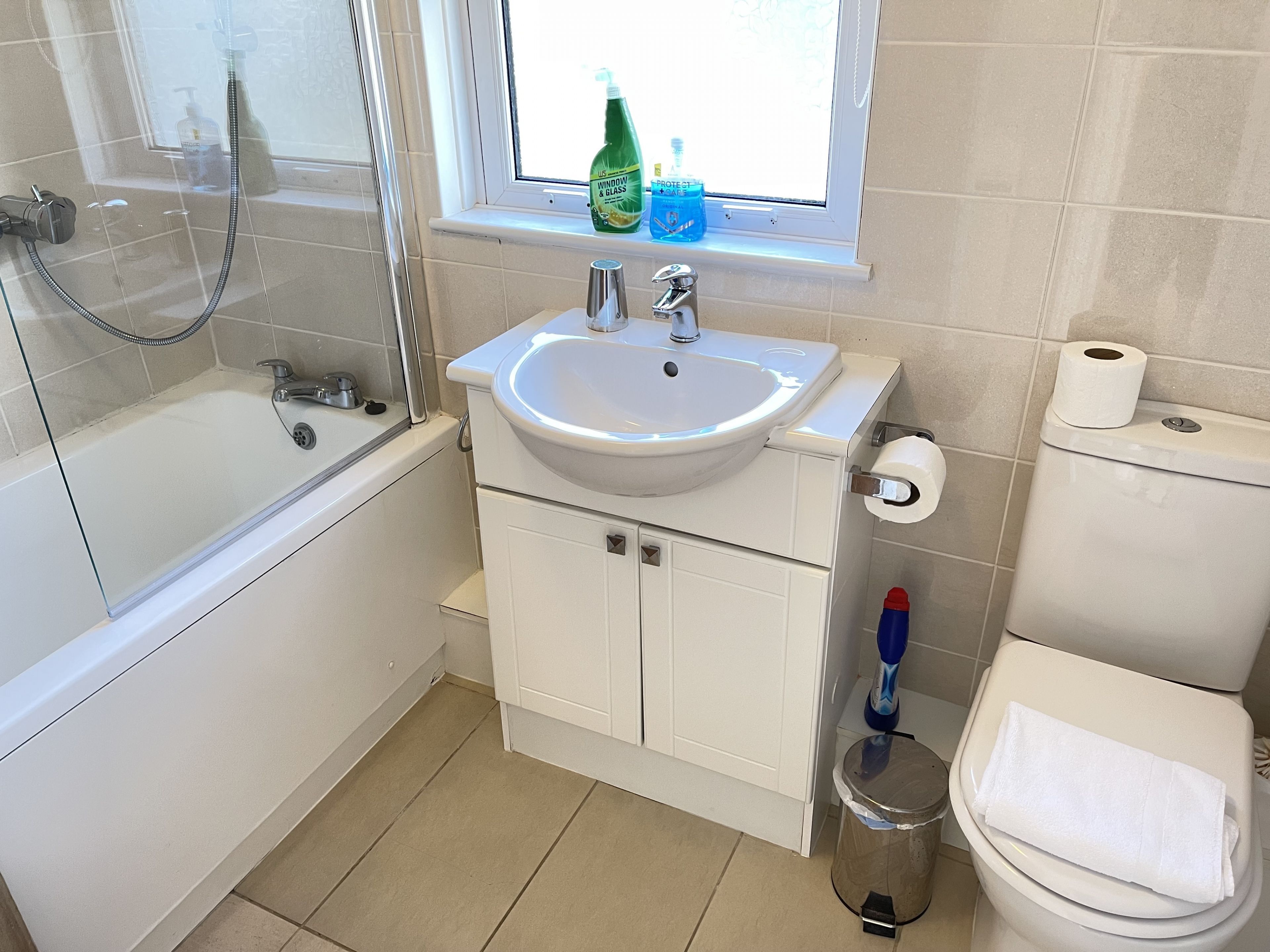 Een badkamer met een bad, wastafel, toilet en raam.