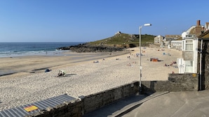 En strand med en stenvæg, en lygtepæl og bygninger i baggrunden.
