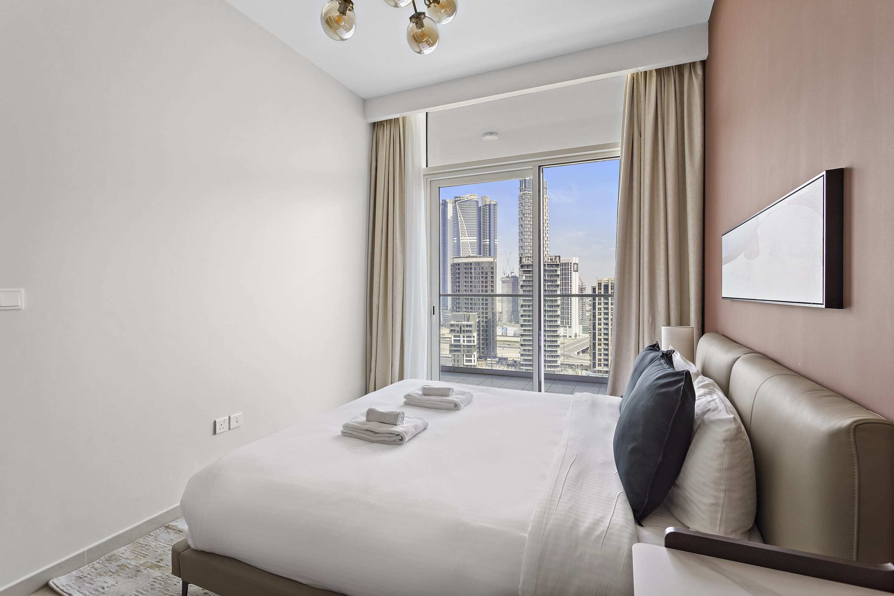 Ein modernes Hotelzimmer mit einem großen Bett, Blick auf die Stadt und einer Kronleuchter.