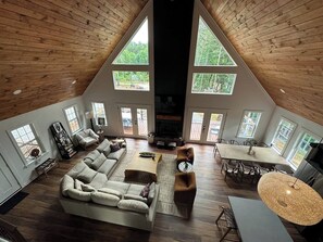 Um loft espaçoso com pé direito alto, um sofá seccional grande, uma mesa de jantar e uma lareira.