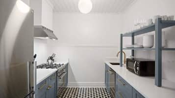 A compact kitchen with a gas stove, microwave, and a black and white patterned floor.
