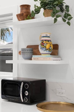 A kitchen with a microwave, a decorative vase, and a plant on the shelf. - Otis Blue at Angels Quarter | Home Steps to 7th! (Tampa)