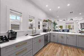 Uma cozinha moderna com armários cinzentos, bancada branca e piso de madeira.