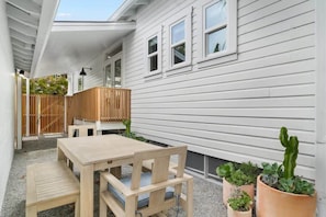 A patio with a wooden table and chairs, a wooden fence, and potted plants.