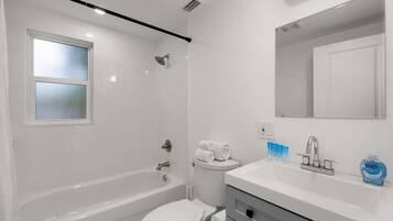 A modern bathroom with a bathtub, toilet, and sink.