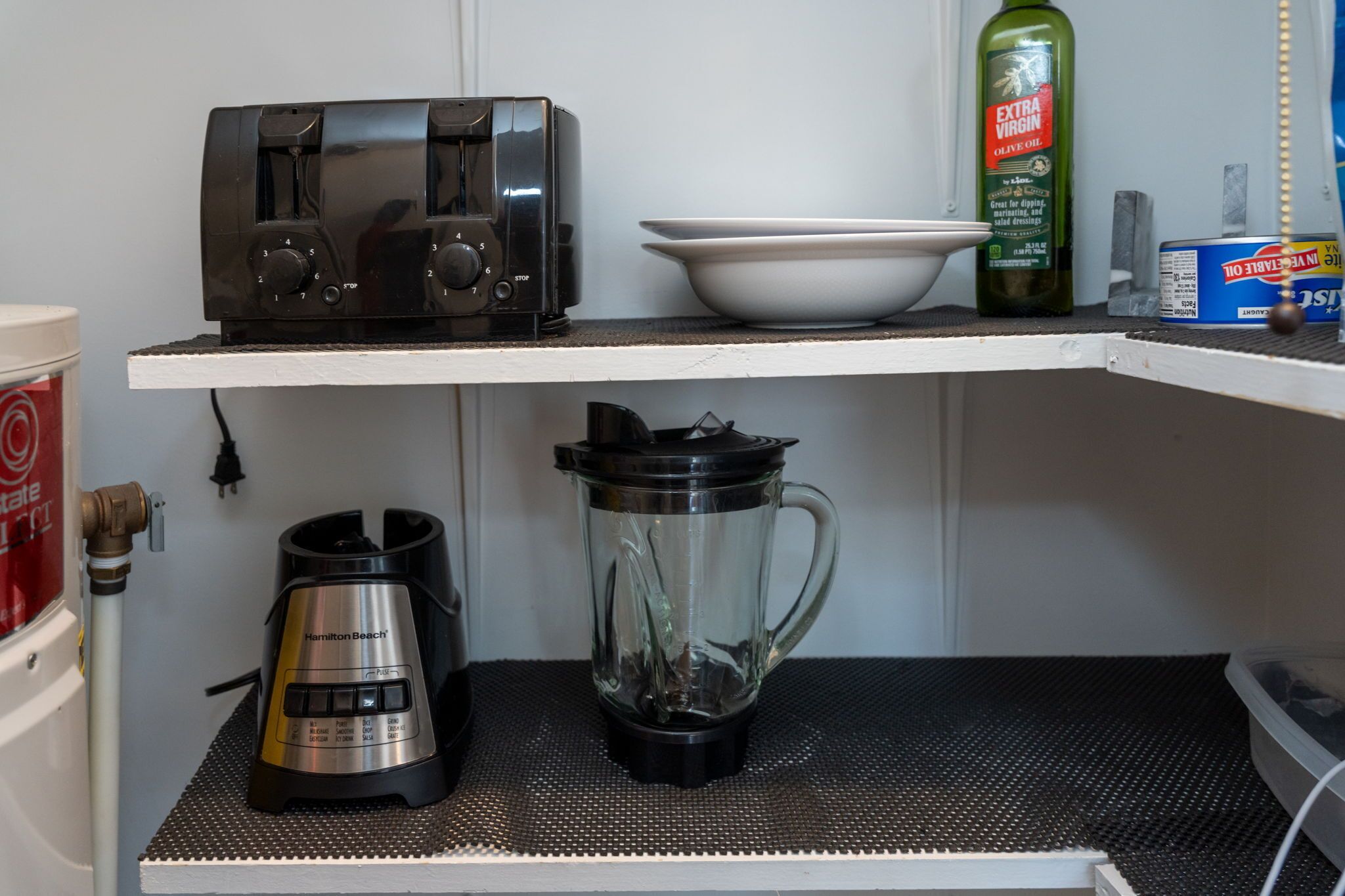 Una encimera de cocina con un tostador, una licuadora, una botella de aceite de oliva y una cafetera.