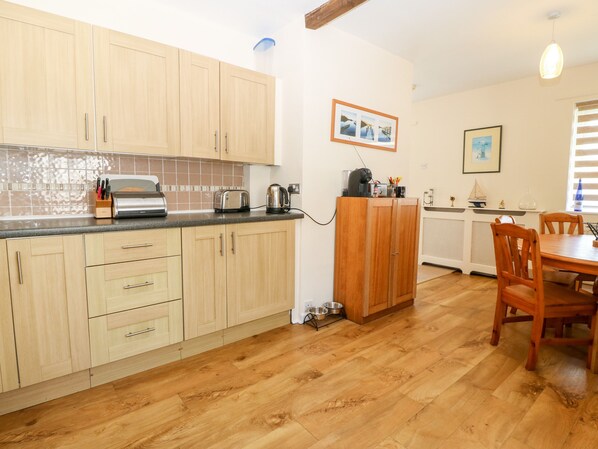 A kitchen with wooden cabinets, a dining table with chairs, and a tiled backsplash.