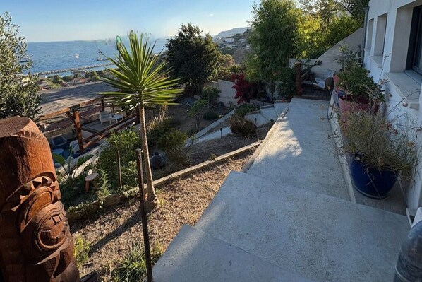 Un balcón con vista al mar, una valla de madera y plantas en macetas.