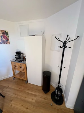 Une cuisine compacte équipée d’un réfrigérateur, d’une machine à café et d’un meuble en bois.