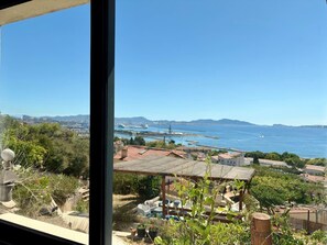 A coastal view with a patio area, a pergola, and a view of the sea and distant mountains.
