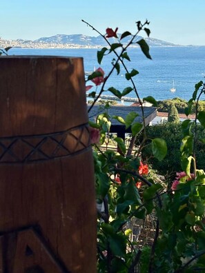 A wooden barrel, a view of the sea, and some greenery.