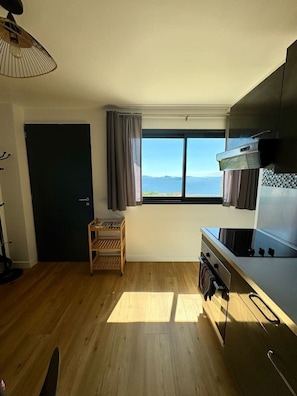 Une cuisine avec vue, un fourneau, une petite table et une porte.