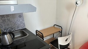 A compact kitchenette with a sink, kettle, and a small wooden shelf. - Apartment in Rosersberg Arlanda Airport (Rosersberg)
