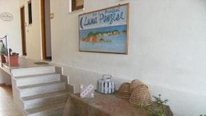 A staircase leading to a room with a table set up with a tablecloth and decorative items. A framed picture of a coastal scene hangs on the wall above the staircase. - Sea Hedgehog Studio (Ponza)