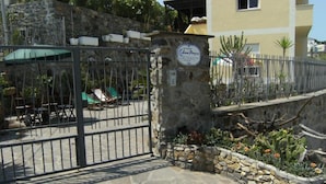 A gated entrance with a stone wall, a sign, and a small garden with cacti and flowers. - Sea Hedgehog Studio (Ponza)