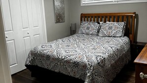 A bedroom with a bed, a ceiling fan, a window with blinds, a door, and a wall-mounted lamp. - 3-bedroom vacation home near Cape Fear River (Lillington)