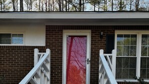 A set of stone steps leading to a door with a red glass panel, flanked by white railings. - 3-bedroom vacation home near Cape Fear River (Lillington)