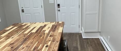 A kitchen with a wooden table, three black barstools, and two white doors.