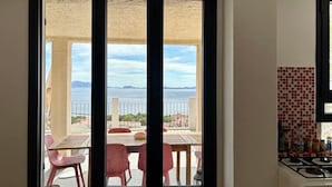 Una cocina con vista a un balcón, un comedor con sillas y un salpicadero de azulejos.