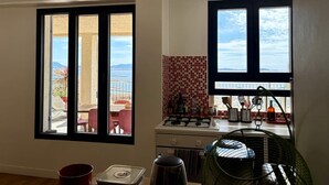 Una cocina con vistas, una zona de comedor con mesa y sillas, y un ventanal pequeño.
