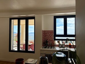Cozinha com vista, área de jantar com mesa e cadeiras, e uma janela pequena.