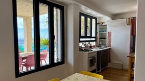 Una habitación con mesa de comedor, zona de cocina y vistas al exterior.