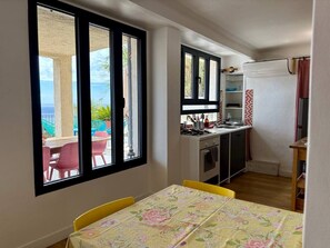 Quarto com mesa de jantar, cozinha e vista para o exterior.