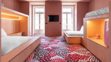 Una habitación de hotel moderna con alfombra estampada, un televisor de pantalla plana y una zona de kitchenette.