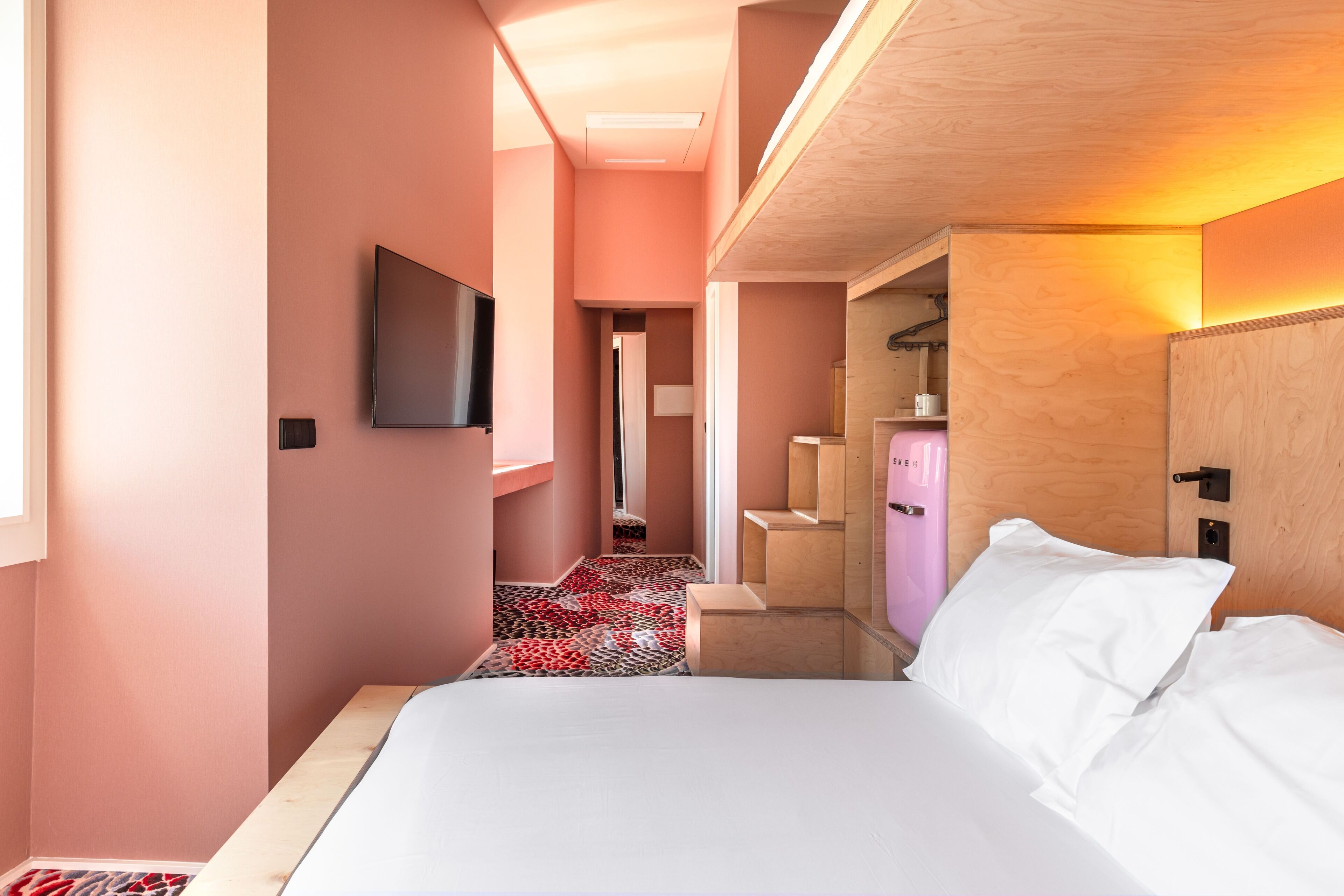 Una camera d'albergo moderna con un letto grande, una TV a schermo piatto, un armadio in legno e un bagno piccolo.