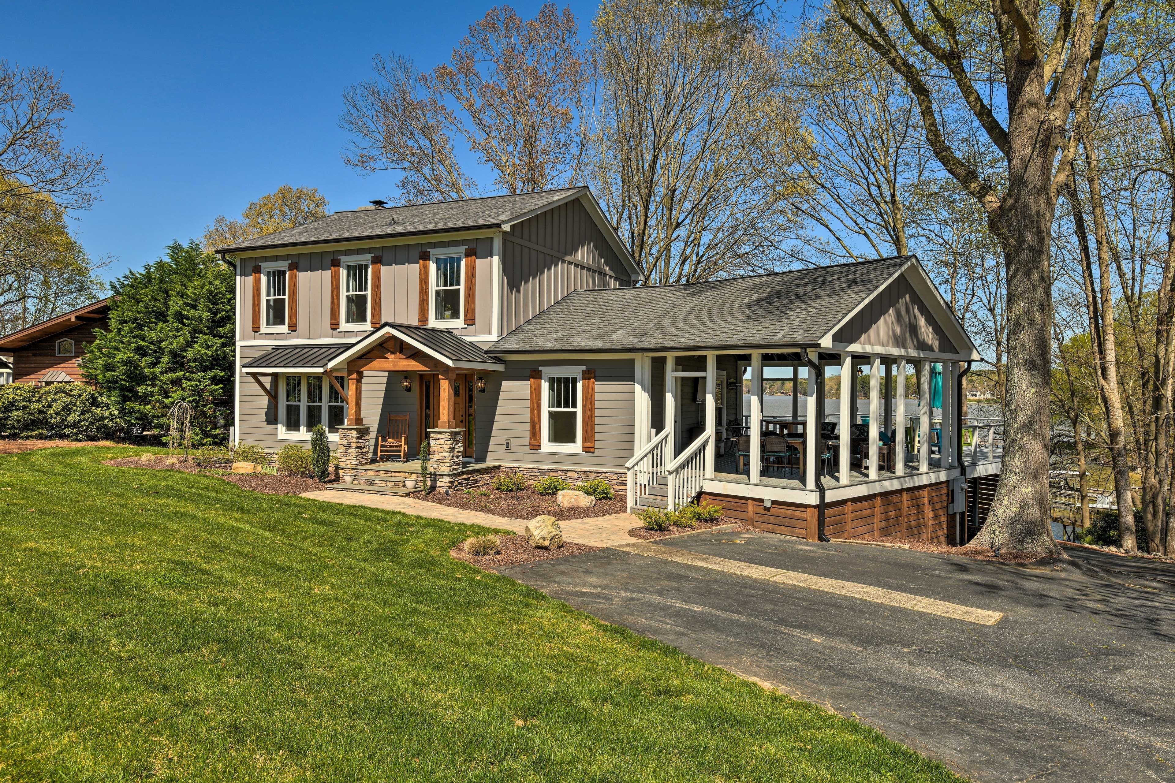 A two-story house with a porch, a covered front porch area, and a large tree in front.