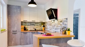 Cozinha moderna com armários cinzas, bancada de madeira e painel de azulejos.