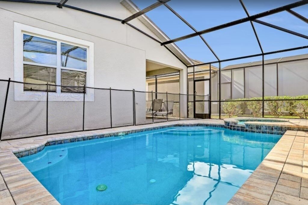A swimming pool with a glass enclosure, a window, and a chair by the pool.