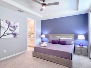A bedroom with a bed, nightstands, a ceiling fan, and a wall painting. - Beautiful 5 Bedroom Town Home with Splash Pool 5 Home by RedAwning (Kissimmee)
