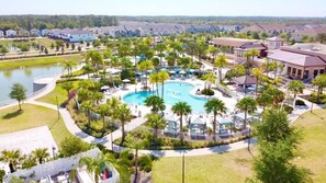 An aerial view of a resort with a central swimming pool, surrounded by palm trees and lounge areas. - Beautiful 5 Bedroom Town Home with Splash Pool 5 Home by RedAwning (Kissimmee)