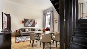 Una sala moderna con una mesa redonda de comedor, un sofá gris y una escalera.