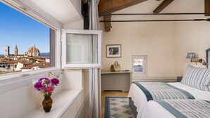 Un dormitorio con vista a un edificio histórico, una mesita de noche con lámpara y una cama con ropa de cama a rayas.