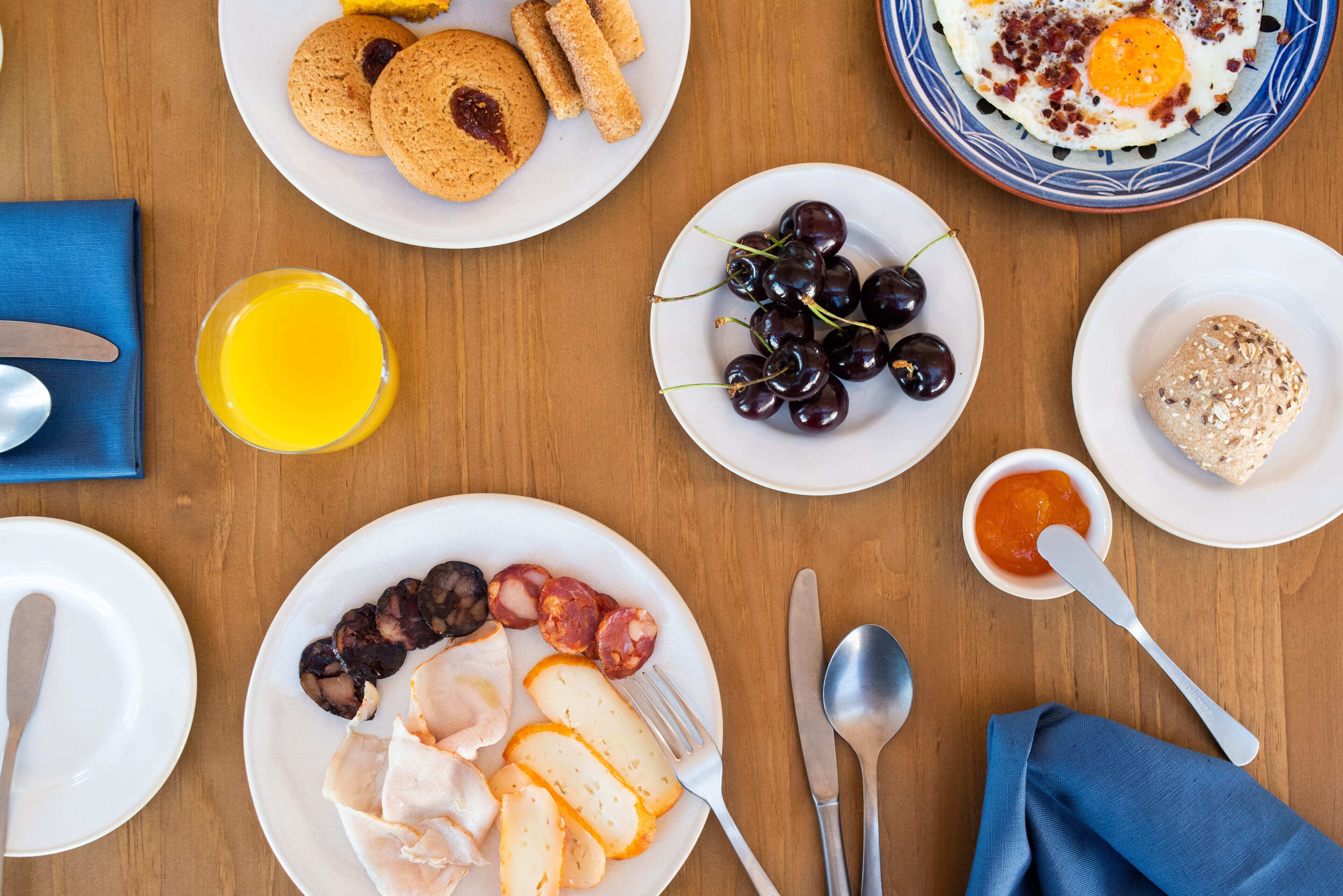 Una mesa de desayuno con platos de comida, incluyendo huevos, salchichas y pan.