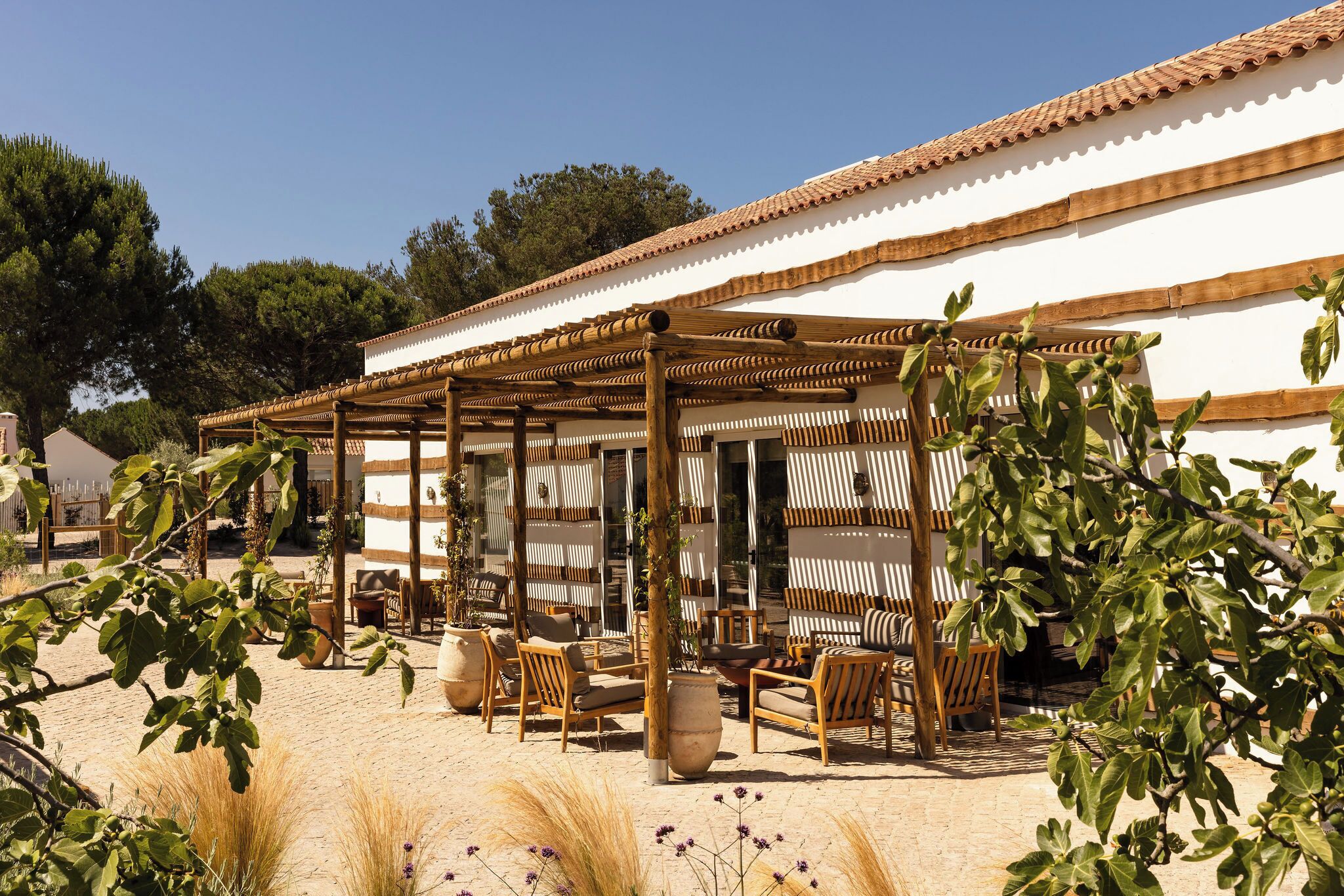 A covered outdoor seating area with wooden furniture and a pergola structure.