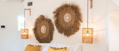 A bedroom with a bed, two wall-mounted lamps, and a round wall decoration.